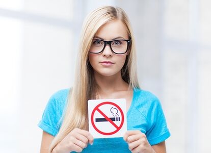 a girl holding a no -smoking sign at the entrance